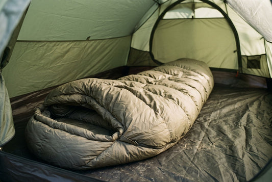 A sleeping bag lying directly on the bare floor of a tent