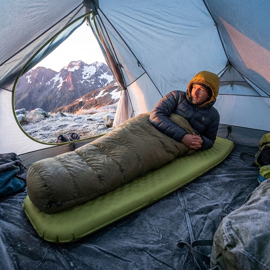 Camper resting on the sleeping pad in a tent