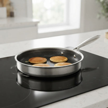 stainless steel frying pan on an induction hob with four evenly browned pancakes