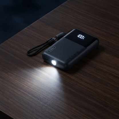 Mini power bank with its built-in flashlight switched on in a dark room