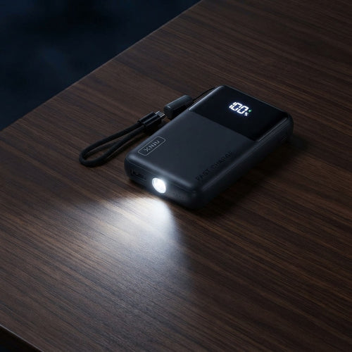 Mini power bank with its built-in flashlight switched on in a dark room