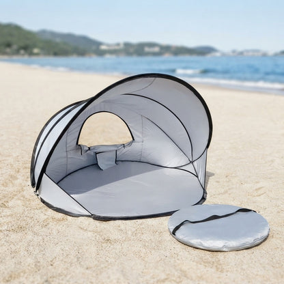 pop up beach tent on sand with its round carry bag beside it